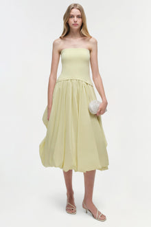 Pale yellow strapless midi dress with fitted bodice and gathered skirt, styled with white beaded clutch and strappy heels.