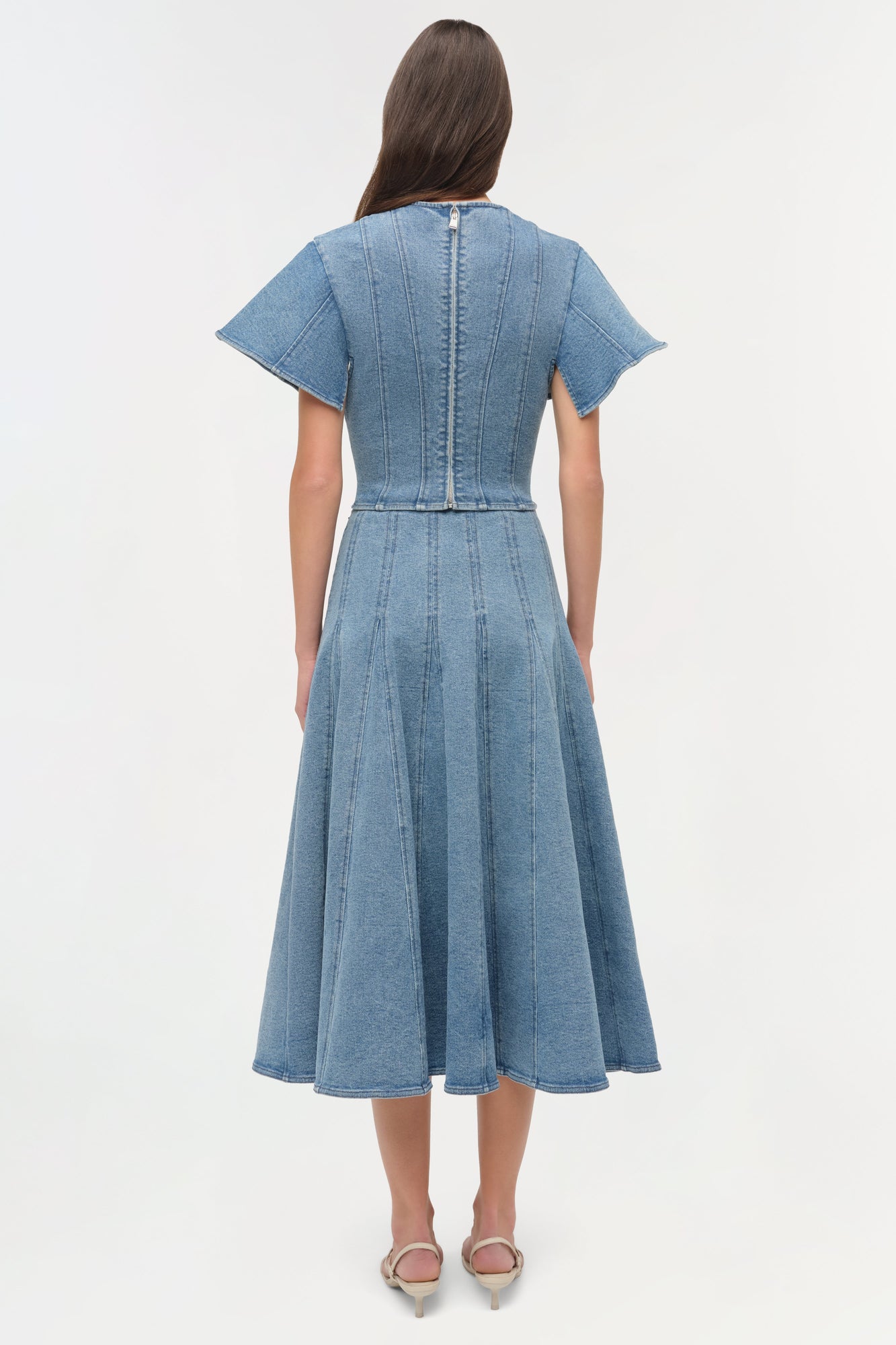 Light blue denim dress with short sleeves, vertical seaming detail, and full skirt shown from back view.