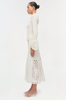 Cream knit midi skirt with cutout embroidered details at cuff and hem, worn with matching long-sleeve top.