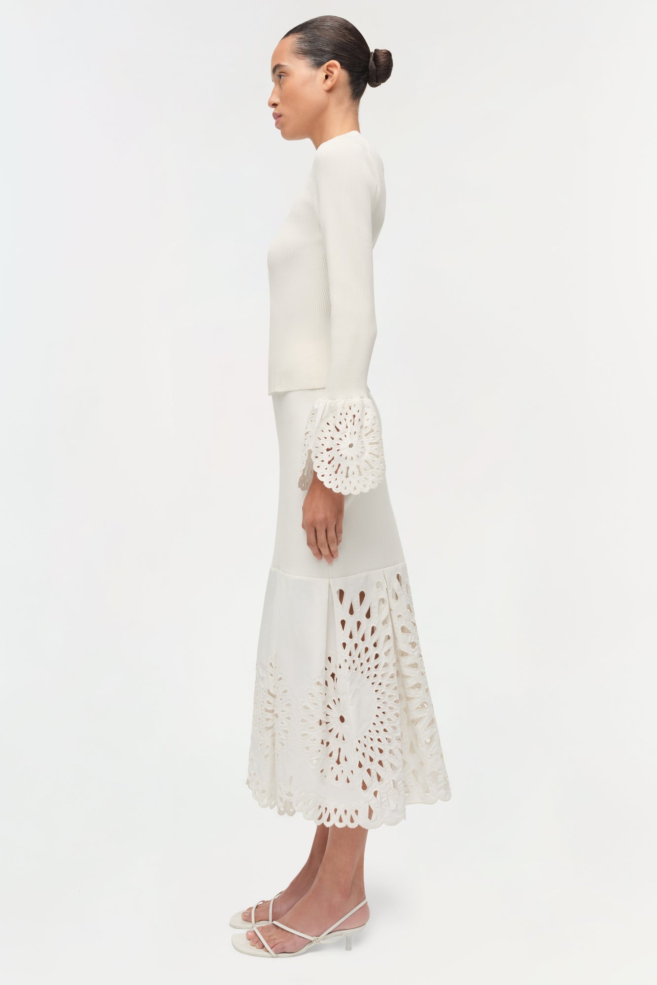 Cream knit midi skirt with cutout embroidered details at cuff and hem, worn with matching long-sleeve top.
