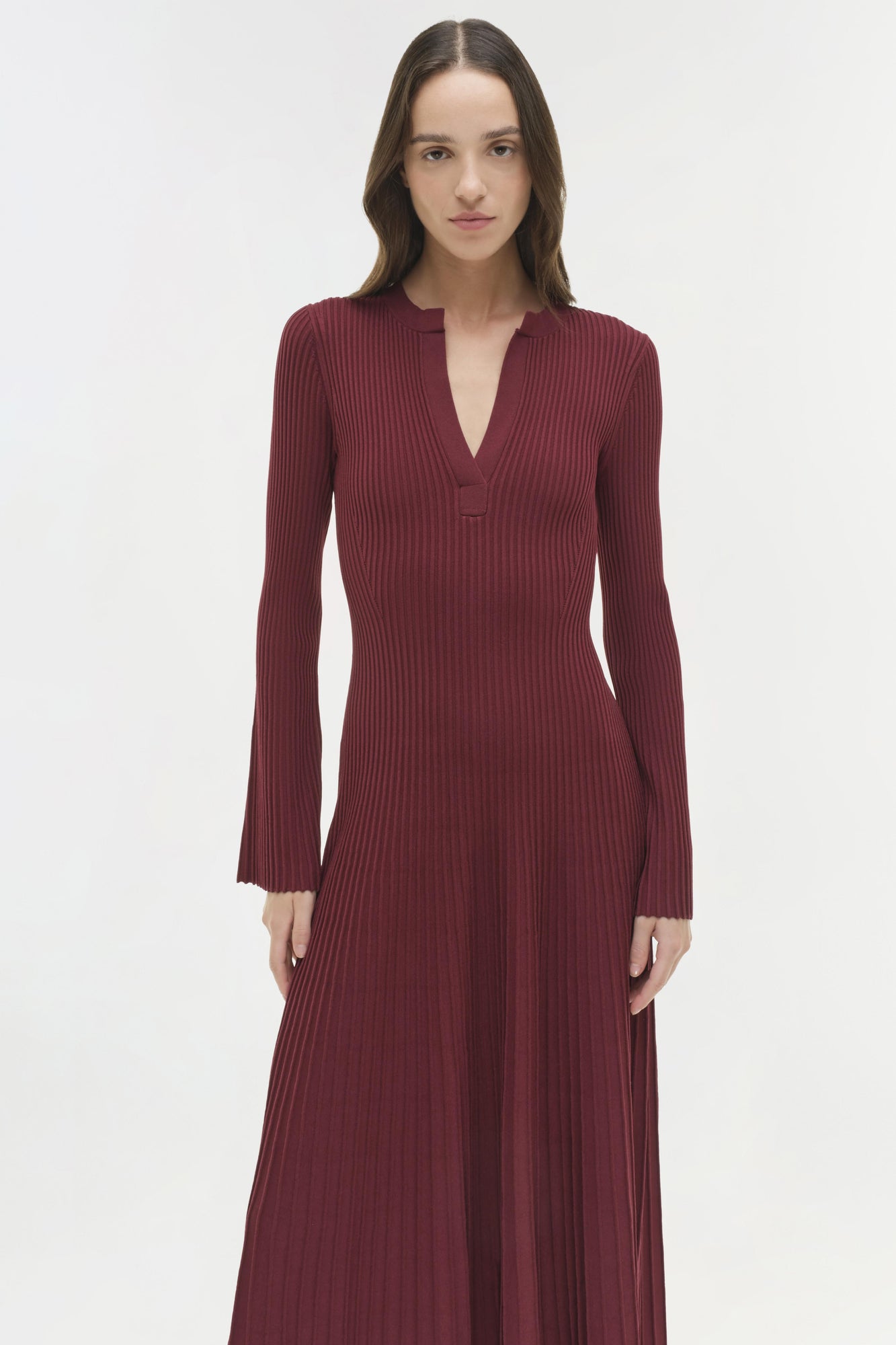 Burgundy ribbed knit midi dress with long sleeves and V-neckline on model against white background.