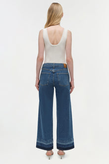 Wide-leg blue denim crop jean with raw hem detail, shown with white sleeveless tank top.