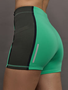 Model wears a pair of bright green activewear bike shorts with gray side paneling. 