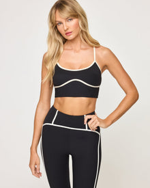 Close-up front view of model wearing the Revel Legging in black-cream showing the waistband with cream trim detail, with matching black-cream Revel Top.