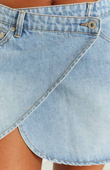 Close-up of the light blue faded denim asymmetrical wrap mini skirt with a button closure