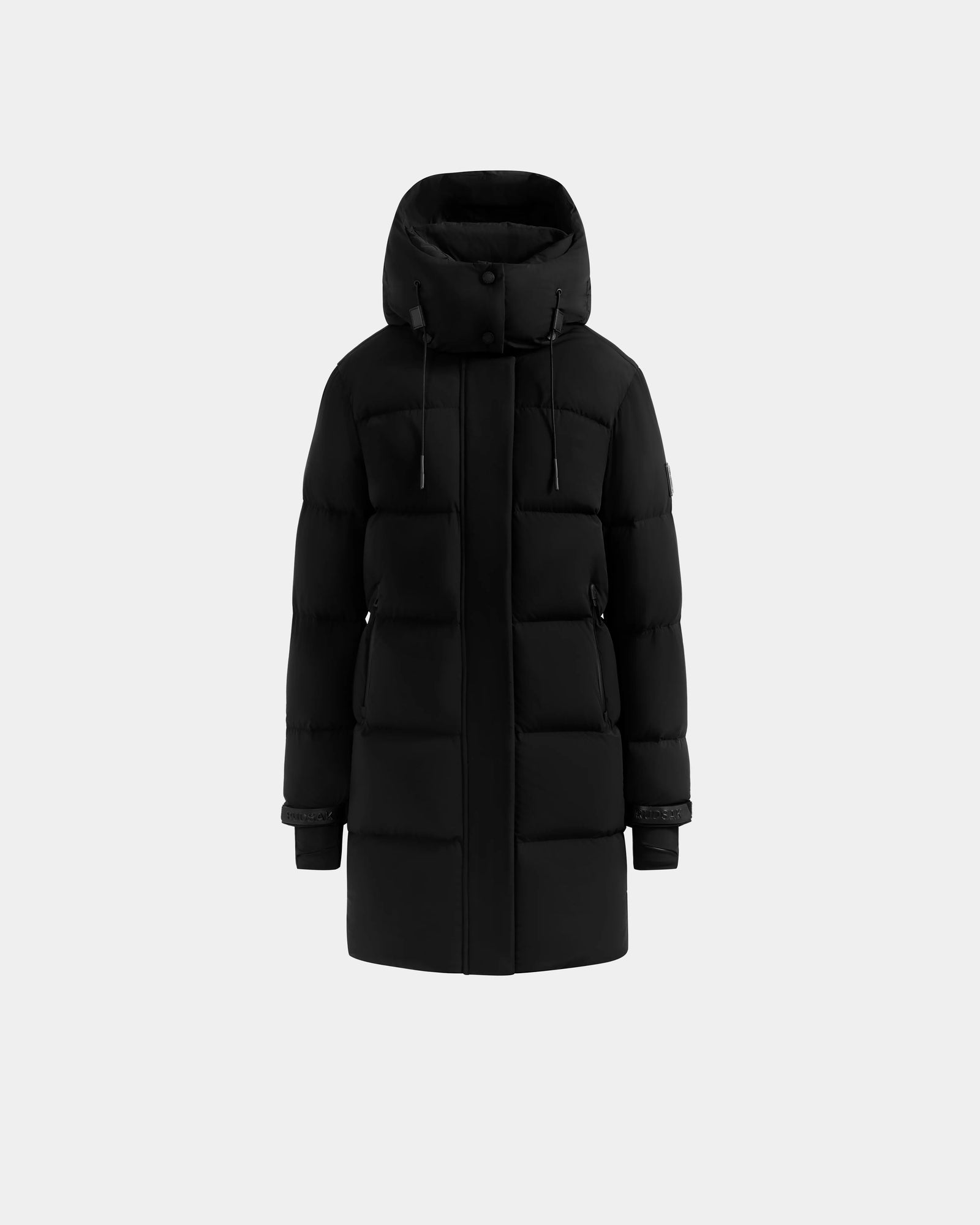 The Rudsak ALESSANDRA M - L125552 Black jacket, a knee-length insulated piece with a hood, front zipper, snap buttons, and two side pockets, is displayed on a plain light gray background.