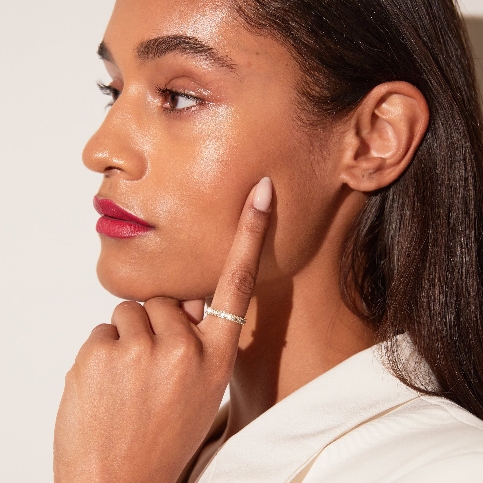 Model. Close up of woman wearing diamond eternity ring on white background