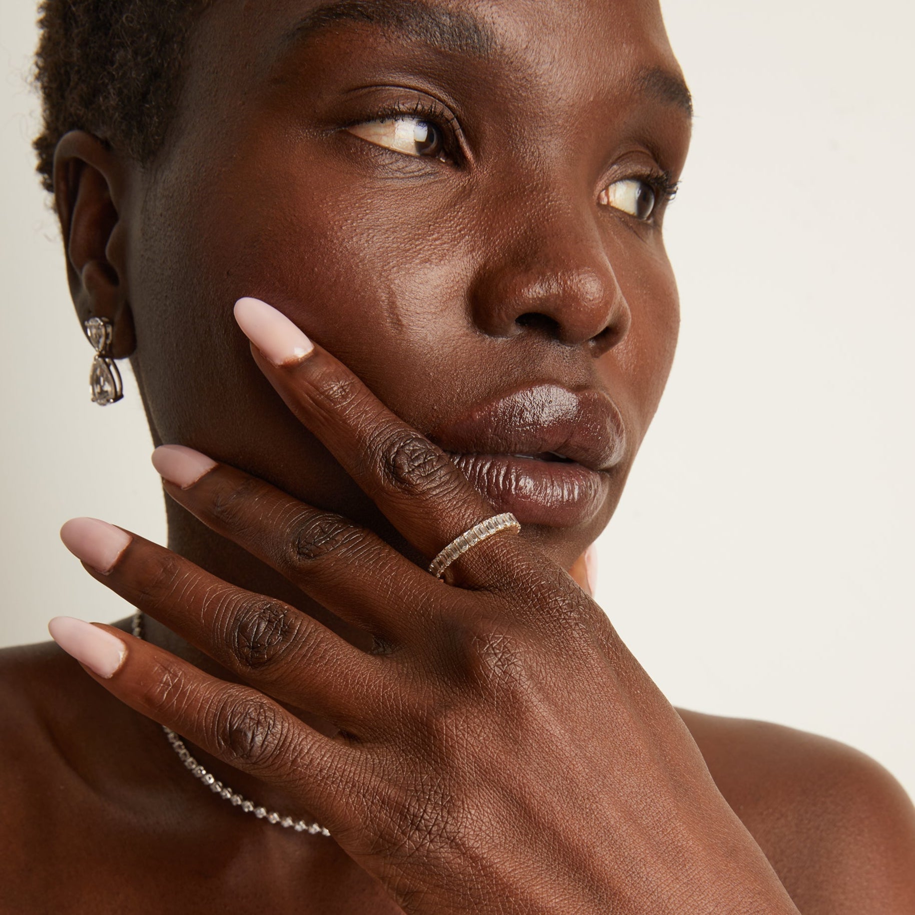Model. Close up of woman wearing diamond eternity ring on white background