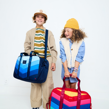 Boy holding STATE Bags Rockaway Duffle Blue Chevron with girl holding STATE Bags Rockaway Duffle Rainbow Chevron