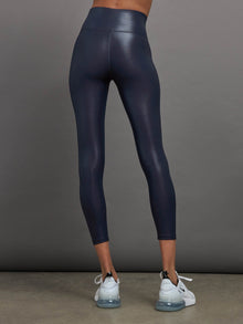 Model is wearing navy high waisted performance leggings in a liquidy-shine finish that hit at mid to low calf.