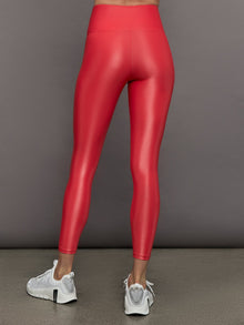 Model wears a high rise pair of bright red leggings with a liquidy shine finish. 