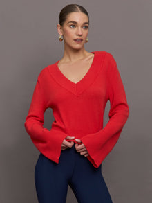 Model wears red off-shoulder sweater with bell sleeve.