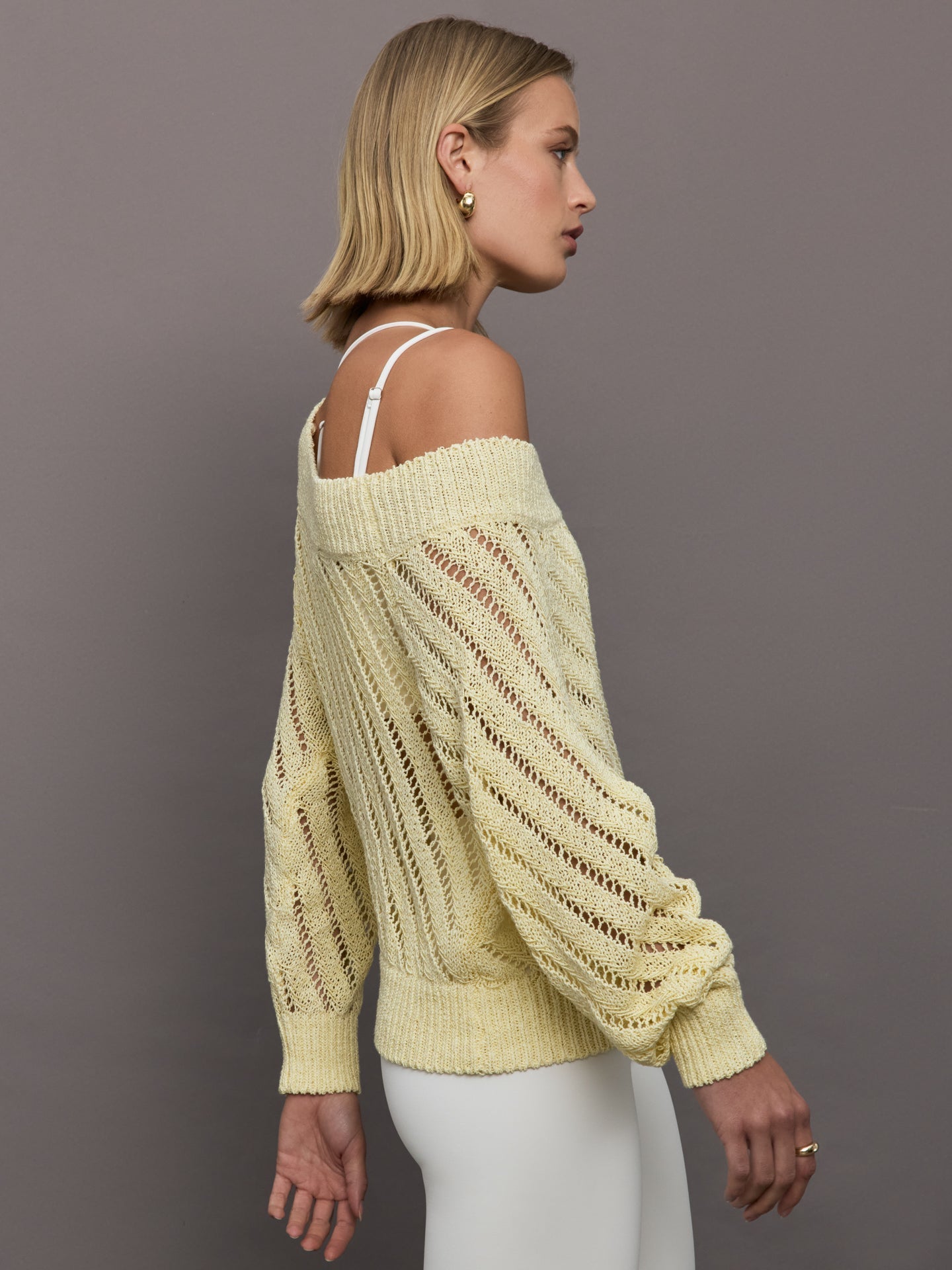 Model wears a yellow off shoulder mesh cardigan with diagonal pattern. 