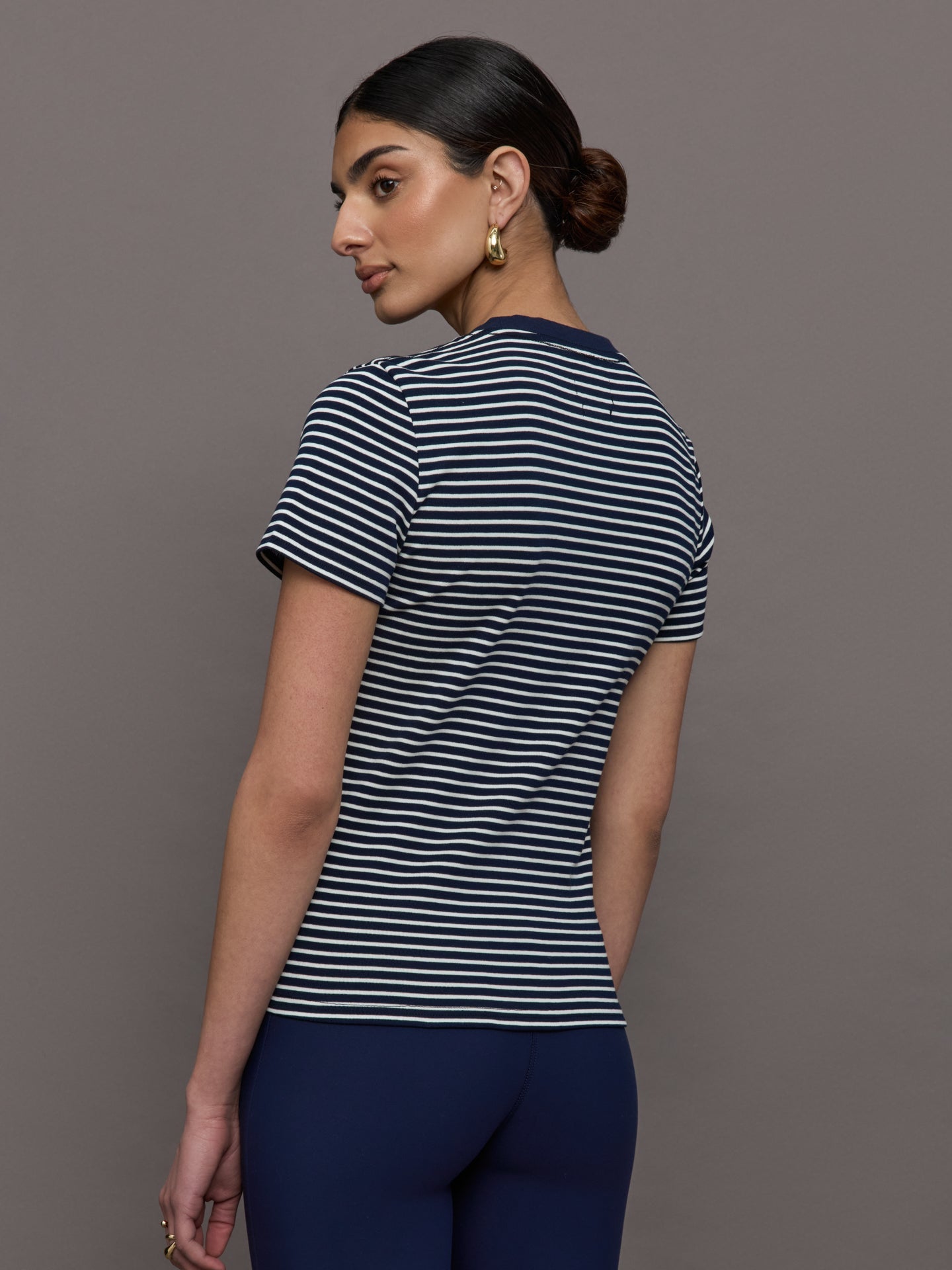 Model wears a navy and white horizontal striped short sleeve ringer tee. 