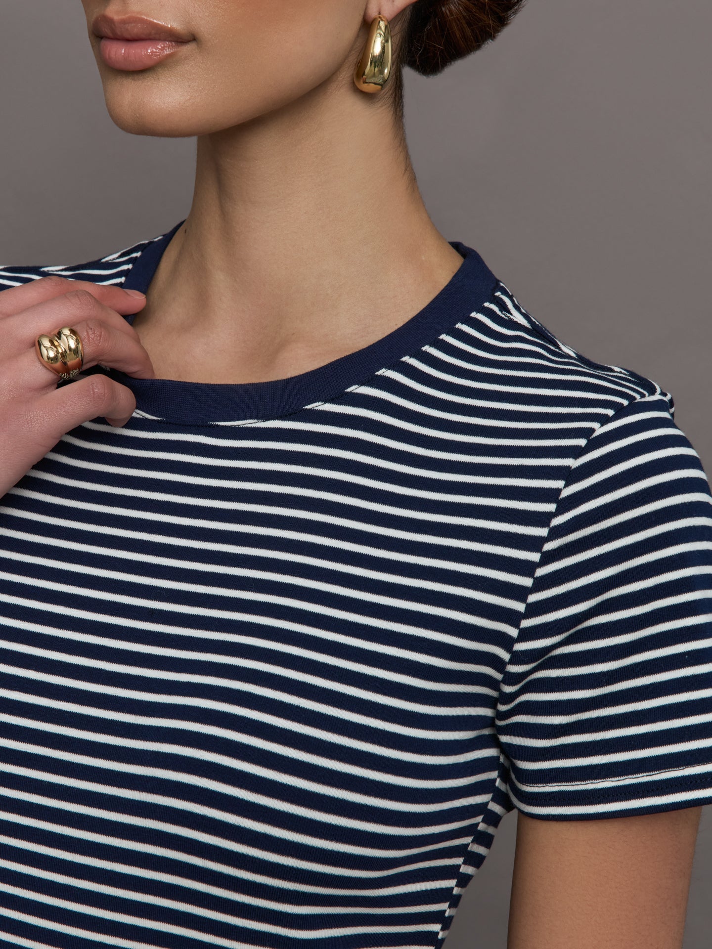 Model wears a navy and white horizontal striped short sleeve ringer tee. 