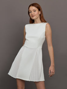 Model wears a white sleeveless tennis dress with pleating below the waist.