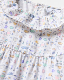 The Kid's Twill Scarlett Nightgown in Baking Spirits Bright features long sleeves, a ruffled collar and cuffs, and a pastel cupcake, teapot, and cutlery print on a white background.