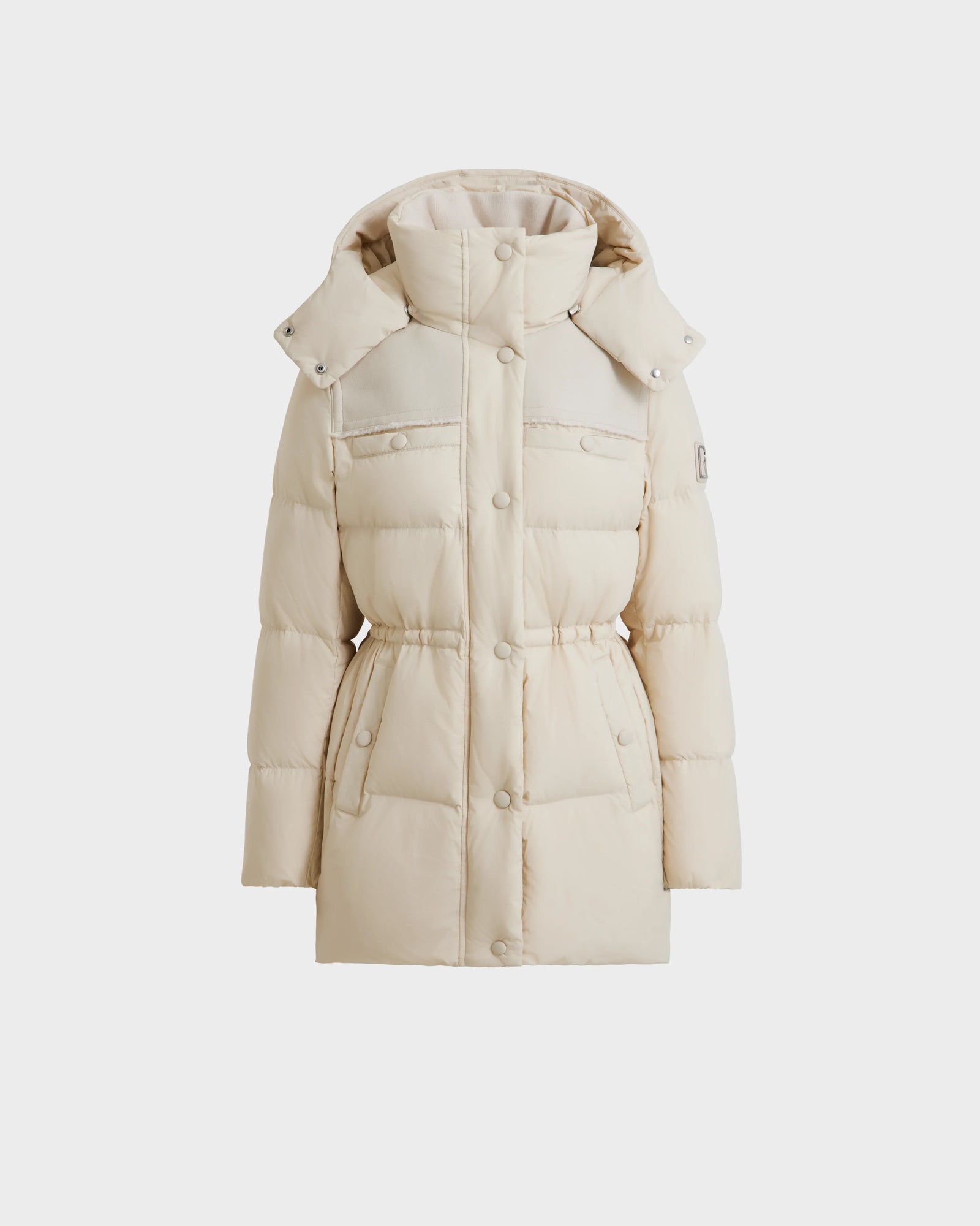 The Rudsak EMBER M-M - L125524 Vanilla is a long, light beige women’s down puffer jacket with a hood, snap buttons, two chest pockets, and a cinched waist, shown against a white background.