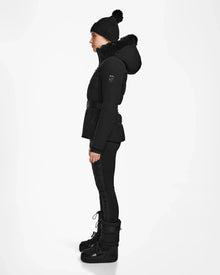 A woman in the Rudsak ALAIA - 8124816 Black quilted ski jacket stands confidently, ready for the slopes with advanced ski-specific features and optional RECCO rescue technology.