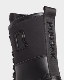 Close-up of the black Rudsak DAMIEN - M222500 men’s winter boot, showing the embossed logo on the pull tab and a raised R emblem. The insulated boot features matte, textured, weather-treated leather.