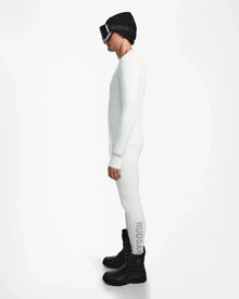 A man in a white Rudsak FRANC - 6524541 Iceland stretch base layer stands in profile, wearing black winter boots, a black beanie, and ski goggles—ready for action against a plain white background.