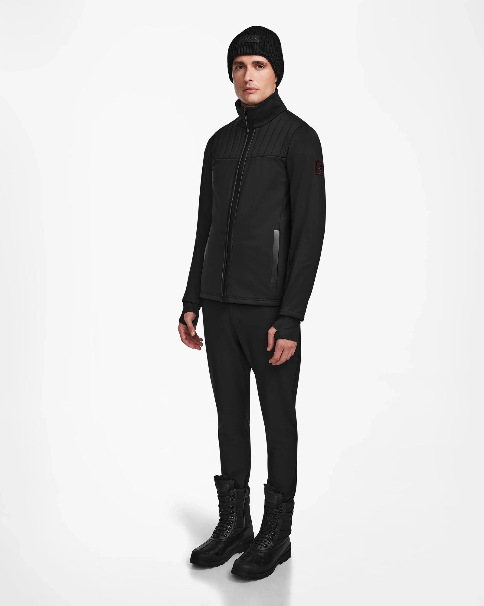 A man wearing black clothes, including the Rudsak TREVOR - 6124519 mens ski jacket designed for technical performance and equipped with RECCO rescue technology.