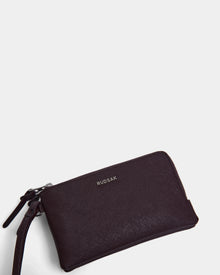 A wine-colored Rudsak ZURIE - L424501 women's leather wristlet wallet with zippered compartments and a wrist strap, displayed on a plain white background.