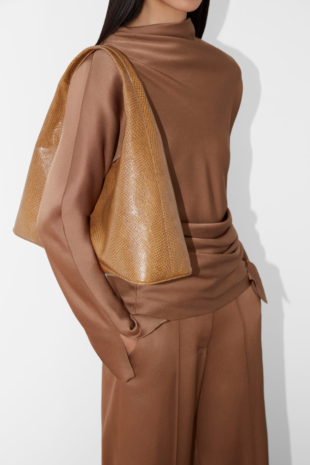 Brown satin top with draped fabric detail across the shoulder and textured gold accent panel.