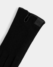 A close-up of the OLGA - L425541 Black women’s glove by Rudsak, featuring soft wool-cashmere lining, elegant stitching, a subtle slit, and a leather patch with embossed text—an essential for cold weather.