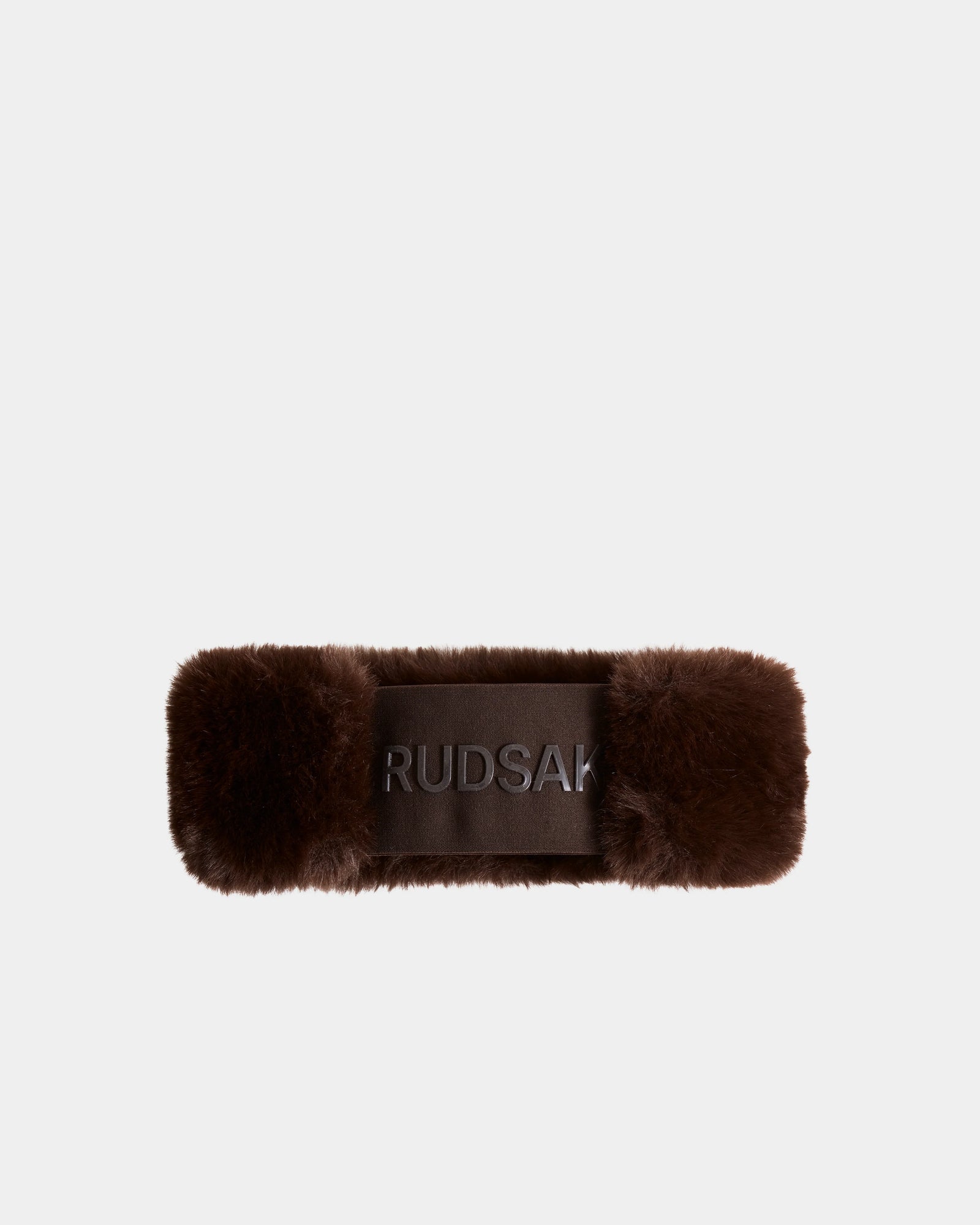 The SANDIE - L425552 Espresso by Rudsak is a brown rectangular faux fur women’s headband with a smooth central panel, featuring the brand name boldly embroidered.