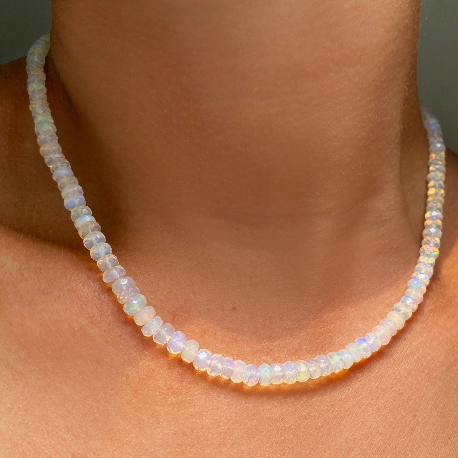 Shimmering beaded necklace made of faceted opals in shades of clear opals on a gold linking ovals clasp.