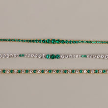 Model. Two gold bracelets with green gemstones on a beige background