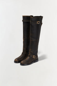 Black and brown distressed leather over-the-knee boots with gold buckle straps and black soles.