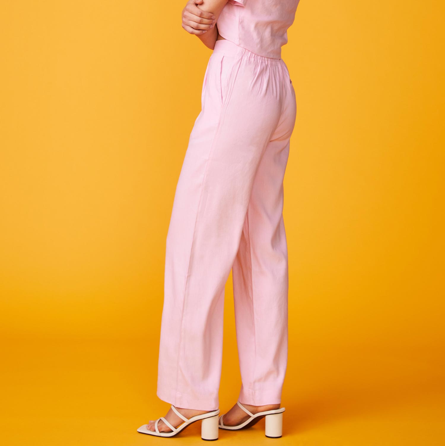 Side view of model wearing the linen pleated pants in bubble gum. 