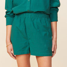 Side view of model wearing the poplin shorts in galapagos green.