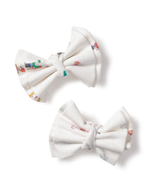 Petite Plumes Girls Twill Hair Bows in A Night at the Nutcracker feature white fabric with colorful patterns, including snowmen and candy canes, set against a plain white background, evoking the enchanting touch of the Sugar Plum Fairy.