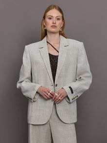 Model wears a gray/taupe textured oversized blazer with single button closure.