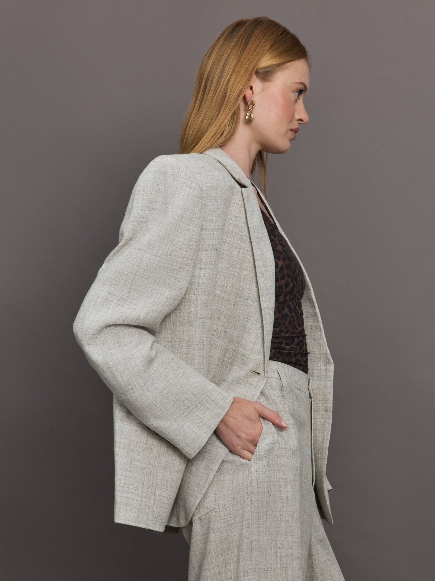 Model wears a gray/taupe textured oversized blazer with single button closure.