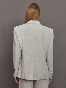 Model wears a gray/taupe textured oversized blazer with single button closure.