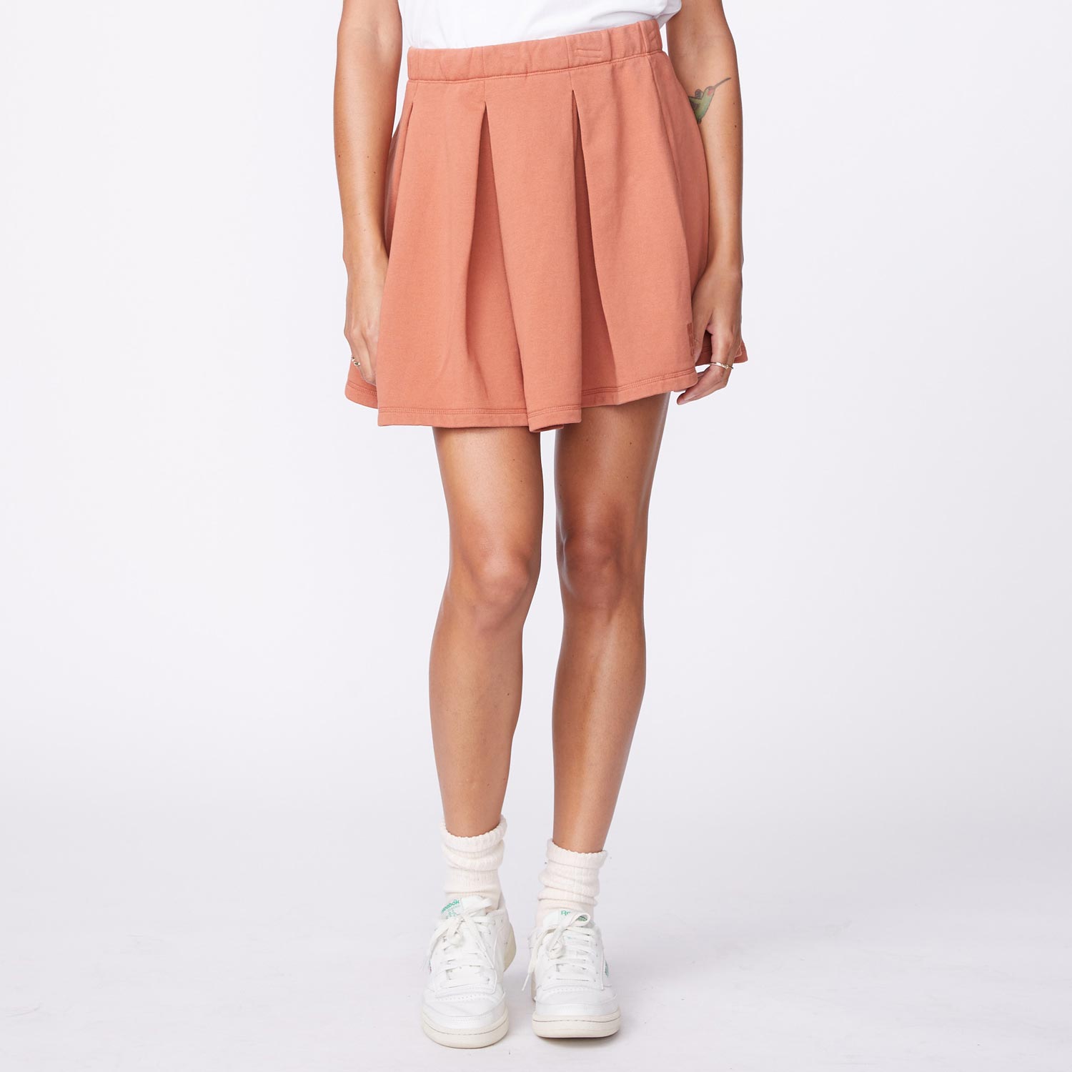 Front view of model wearing the 90's classic tennis skirt in faded rust.