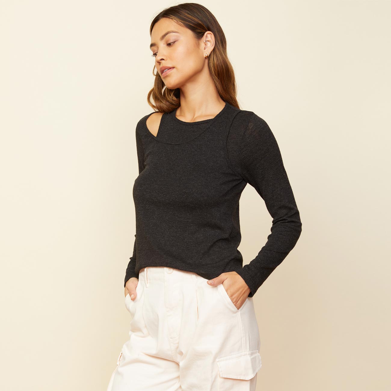 Side view of model wearing the asymmetric long sleeve top in black.