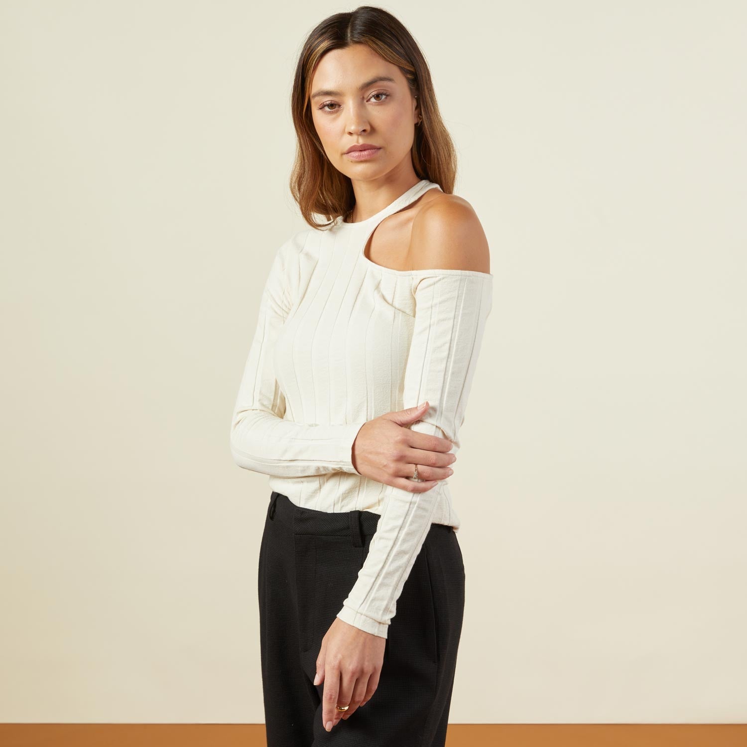 Side view of model wearing the flat rib asymmetric long sleeve in off white.