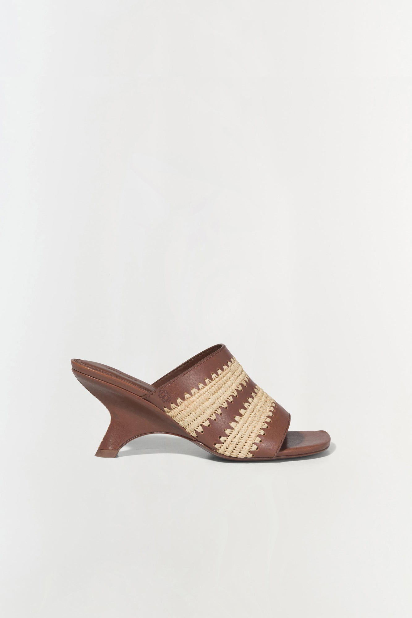 Brown leather mule sandal with woven raffia striped detailing across the upper and curved wedge heel.