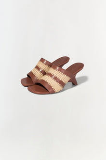 Brown leather mule sandal with woven raffia striped upper and curved heel.