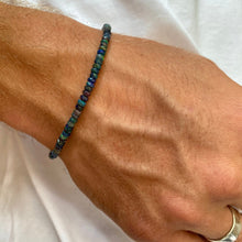 Shimmering beaded bracelet made of faceted opals in shades of black, blue, and green on a gold linking lobster clasp.