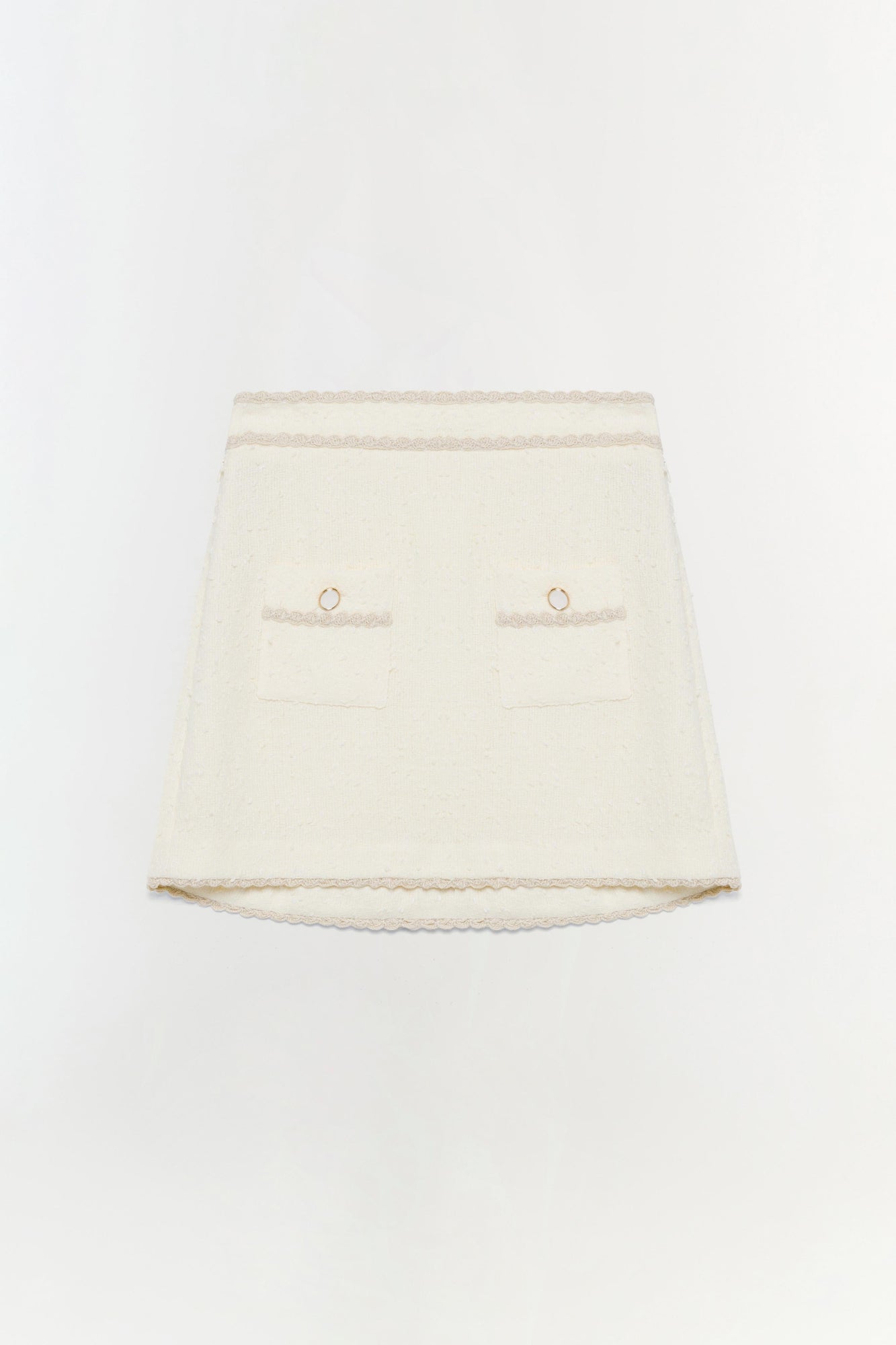 Cream mini skirt with lace trim, two front pockets with circular metal details, and curved hem.