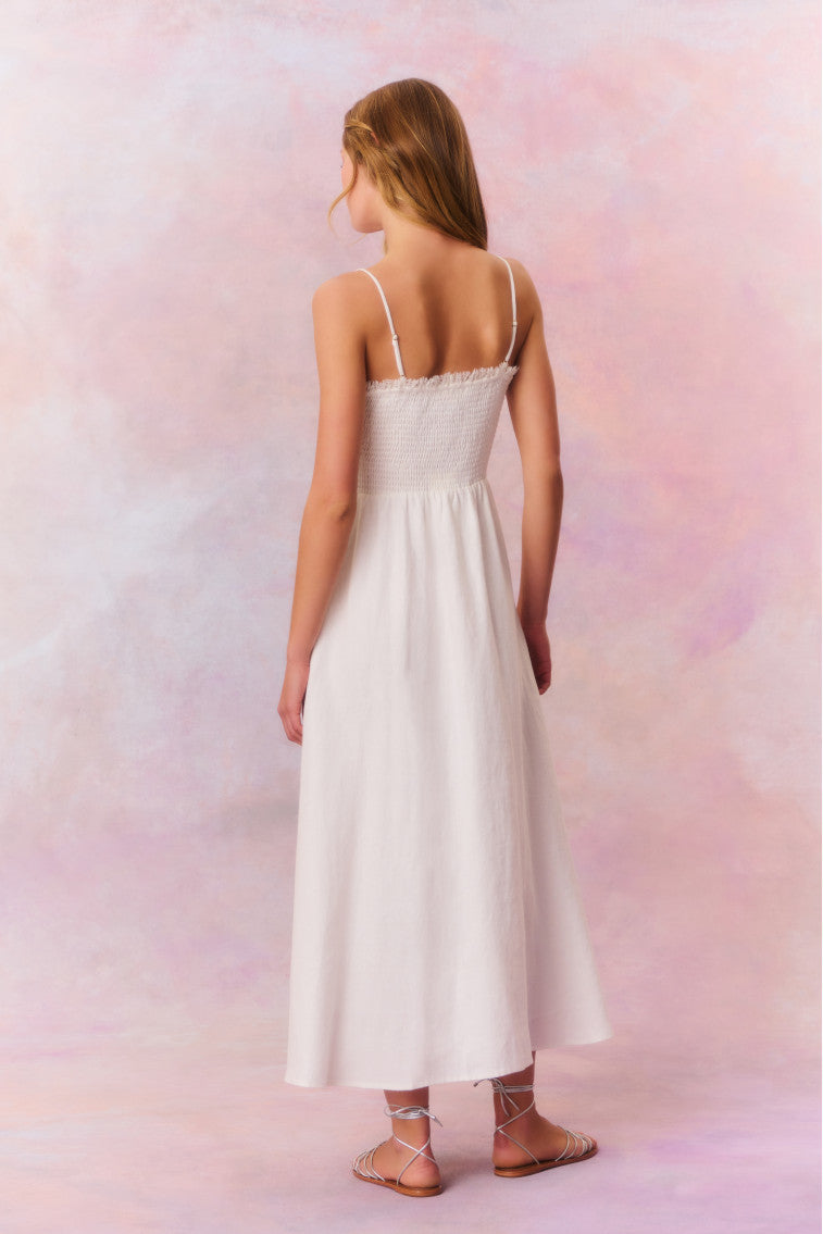 White maxi dress featuring thin spaghetti straps, bustier-inspired cups at the bust with shirring details, a playful keyhole cutout, a center front placket that stops at the hip above a center front slit.