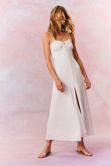 White maxi dress featuring thin spaghetti straps, bustier-inspired cups at the bust with shirring details, a playful keyhole cutout, a center front placket that stops at the hip above a center front slit.