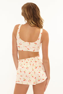 Woman wearing a two-piece swimsuit with cherry pattern on a white background