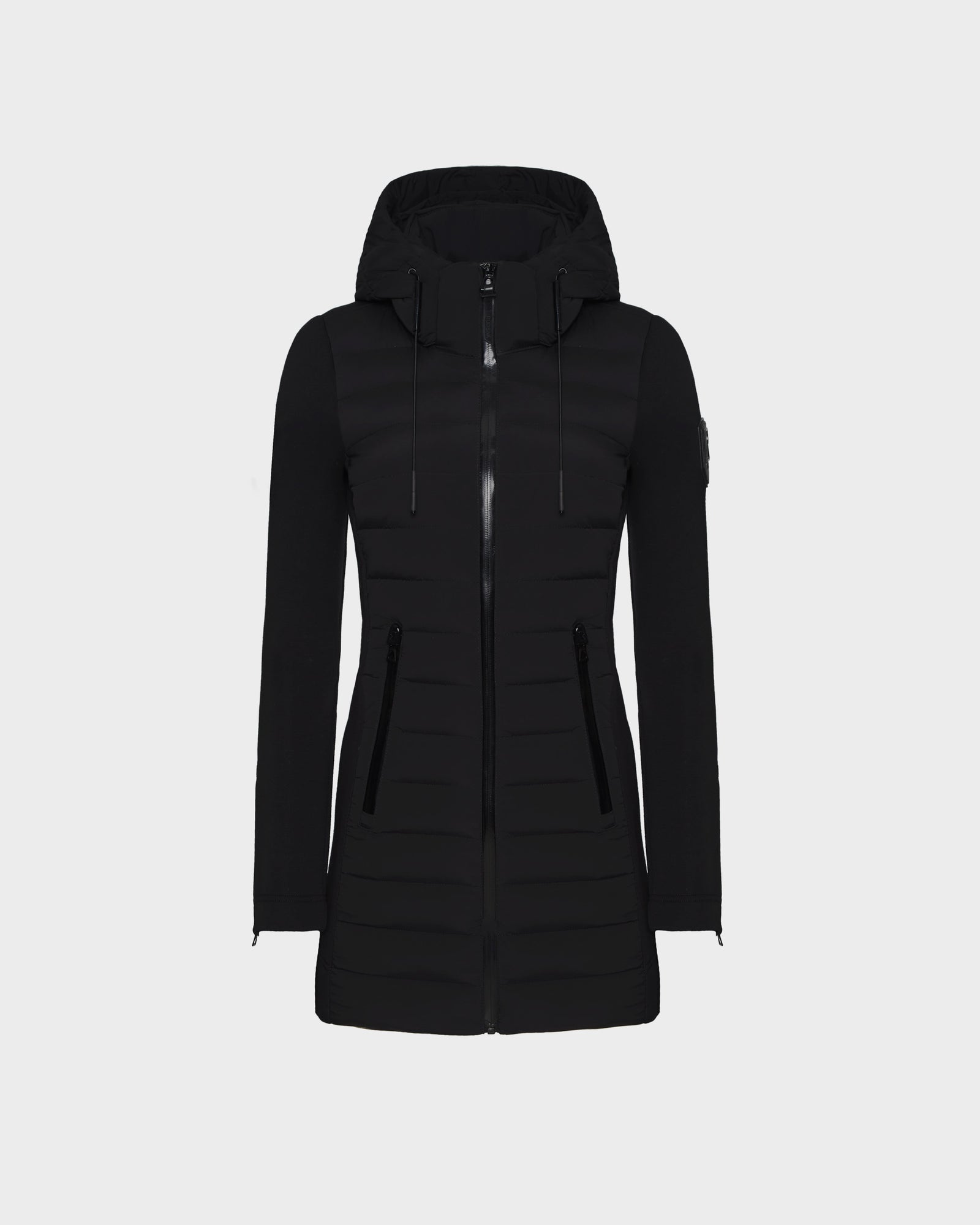 The RUDSAK MERINA - 8122546 BLACK is a long black quilted down jacket with horizontal quilting, front zipper closure, zippered side pockets, and a sleeve patch—ideal as a transitional winter jacket.